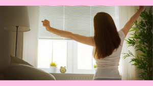 ベッドに腰掛けて背伸びをする女性